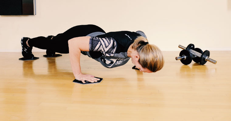 Trainerin beim Liegestütz auf Slide-Pads
